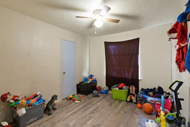 playroom featuring ceiling fan, hardwood / wood-style floors, and a textured ceiling