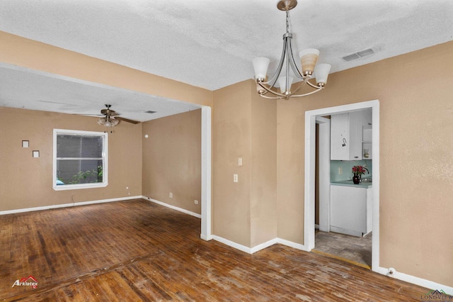 spare room with ceiling fan with notable chandelier, dark hardwood / wood-style flooring, and a textured ceiling