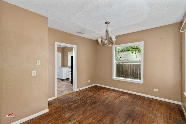 unfurnished room featuring dark hardwood / wood-style flooring, a textured ceiling, and an inviting chandelier