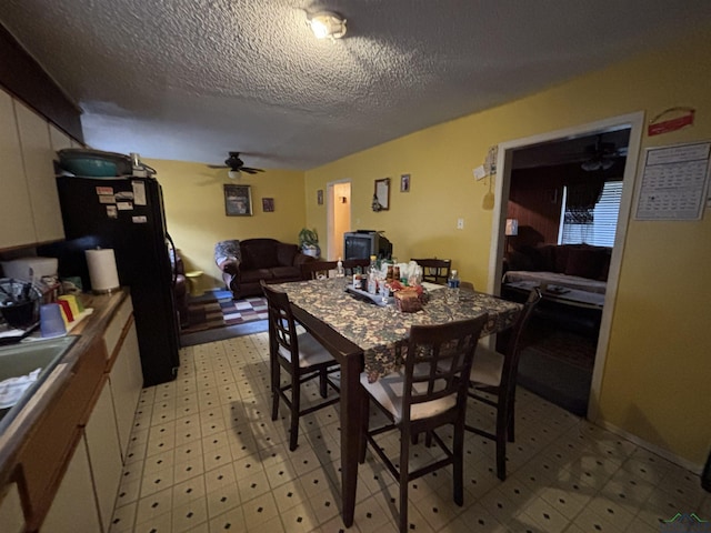 dining area featuring a textured ceiling, light floors, and a ceiling fan