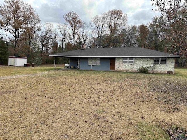 single story home with a carport, a front yard, and an outbuilding