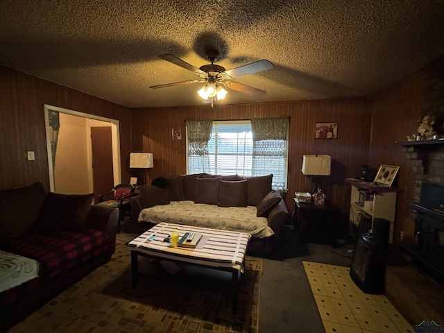 living room with ceiling fan, a textured ceiling, a fireplace, and wooden walls