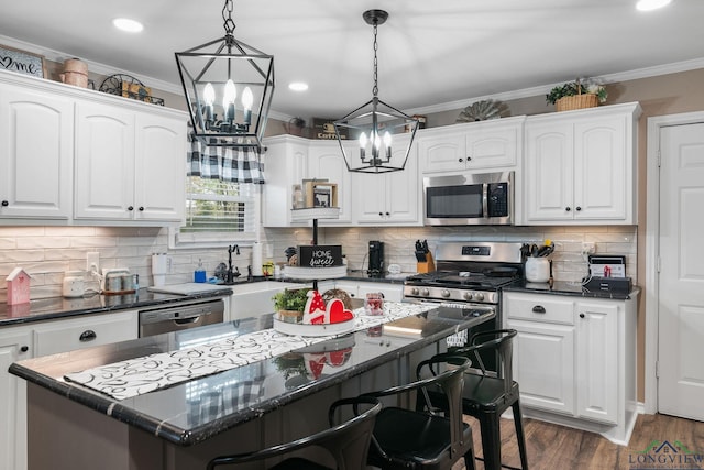 kitchen featuring white cabinetry, decorative light fixtures, a kitchen island, and appliances with stainless steel finishes