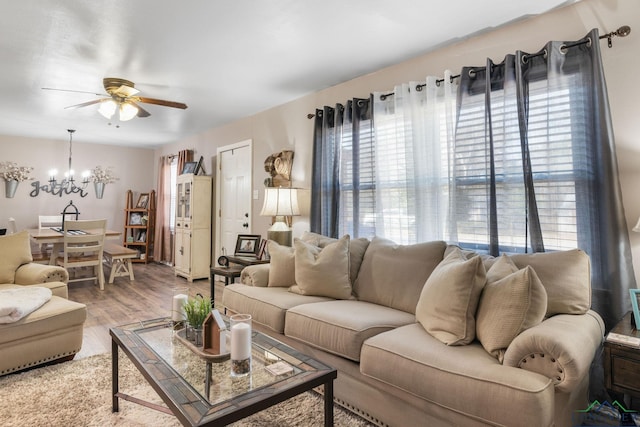 living room with wood-type flooring, plenty of natural light, and ceiling fan with notable chandelier