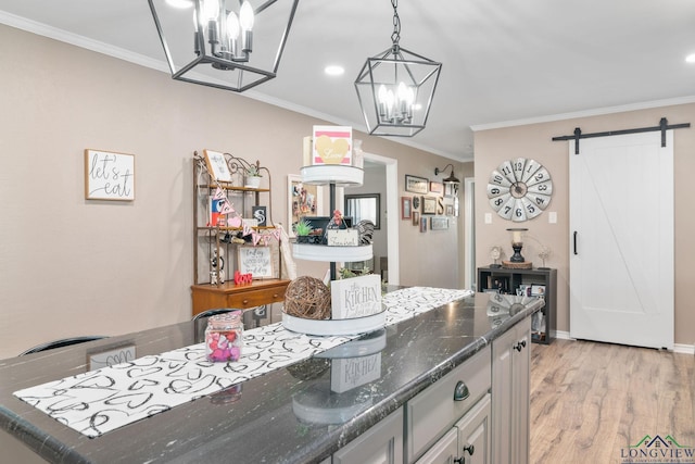 kitchen featuring white cabinetry, dark stone counters, light hardwood / wood-style floors, crown molding, and a barn door