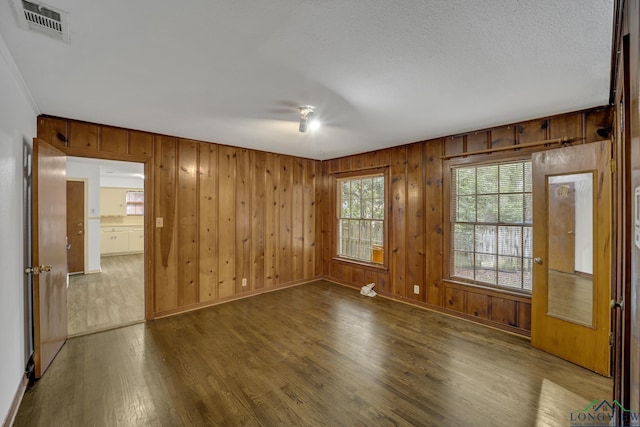 spare room with hardwood / wood-style floors, wood walls, and crown molding