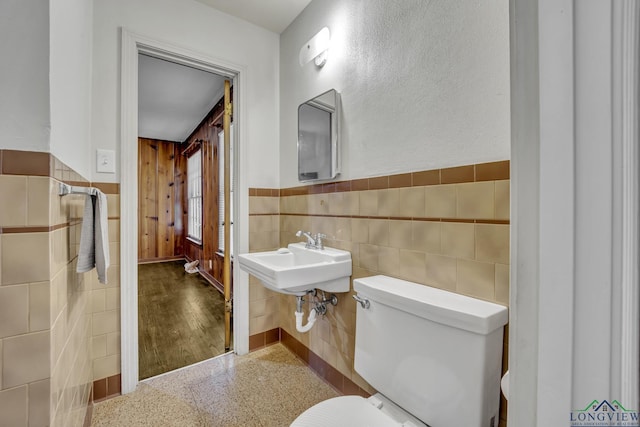 bathroom featuring toilet, sink, and tile walls