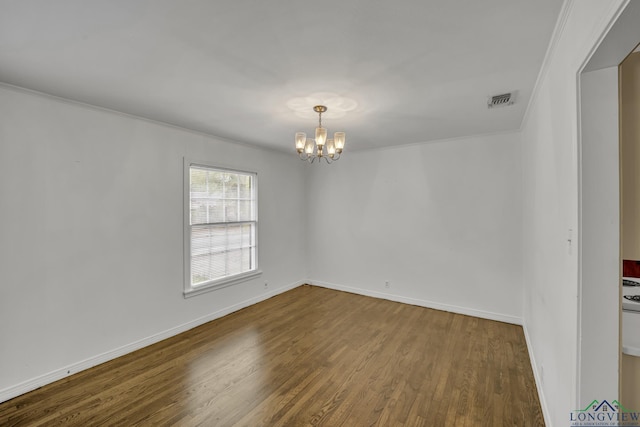 spare room with a notable chandelier and dark hardwood / wood-style flooring