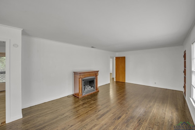 unfurnished living room with dark hardwood / wood-style flooring and ornamental molding