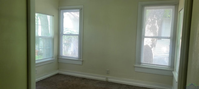 spare room featuring dark carpet