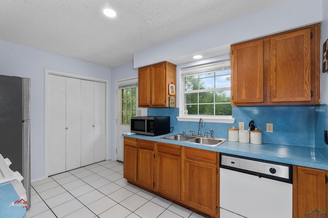 kitchen with appliances with stainless steel finishes, a textured ceiling, light tile patterned floors, and sink