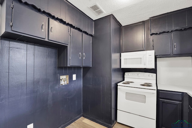 kitchen with a textured ceiling, white appliances, and light hardwood / wood-style floors