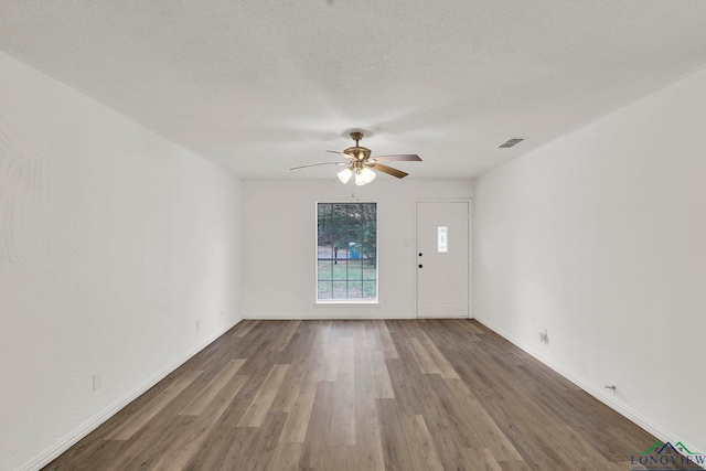 empty room with dark hardwood / wood-style floors, ceiling fan, and a textured ceiling