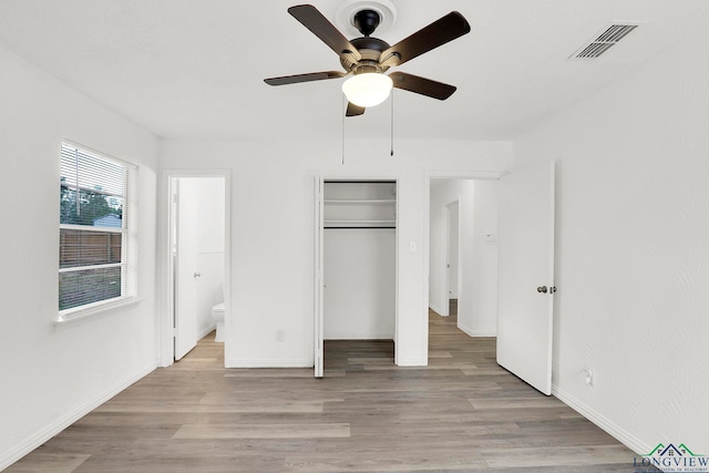 unfurnished bedroom featuring ceiling fan, a closet, connected bathroom, and light hardwood / wood-style flooring