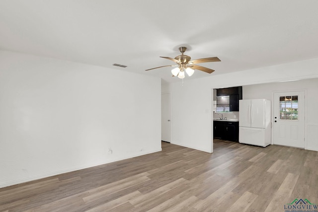 unfurnished living room featuring light hardwood / wood-style flooring, ceiling fan, and sink