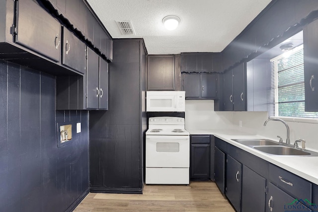 kitchen featuring a textured ceiling, white appliances, light hardwood / wood-style flooring, and sink