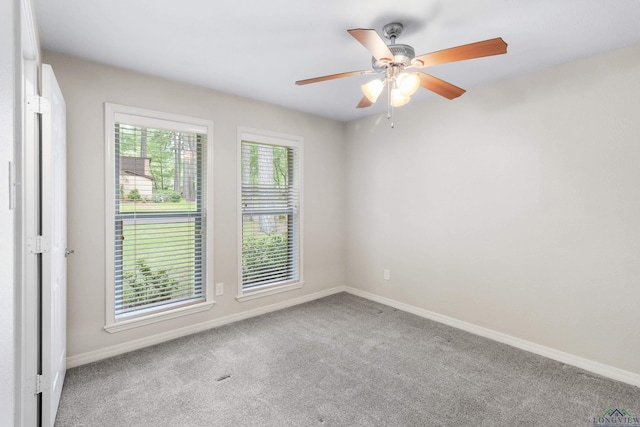 carpeted empty room featuring a ceiling fan and baseboards