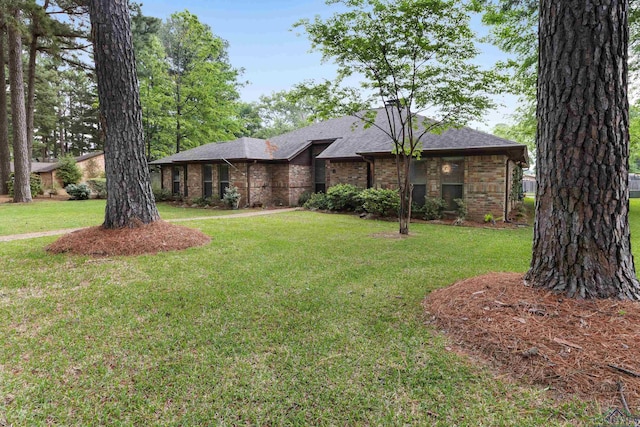 view of front of property with brick siding, roof with shingles, and a front lawn