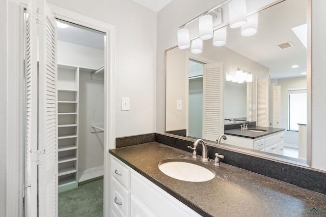 full bath with a walk in closet, vanity, and visible vents