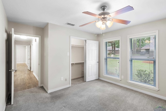 unfurnished bedroom with a ceiling fan, a spacious closet, baseboards, carpet flooring, and visible vents