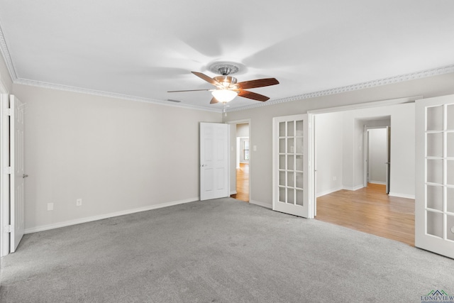 empty room featuring light carpet, a ceiling fan, visible vents, and crown molding