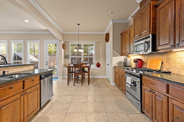 kitchen with sink, a notable chandelier, backsplash, dark stone countertops, and appliances with stainless steel finishes