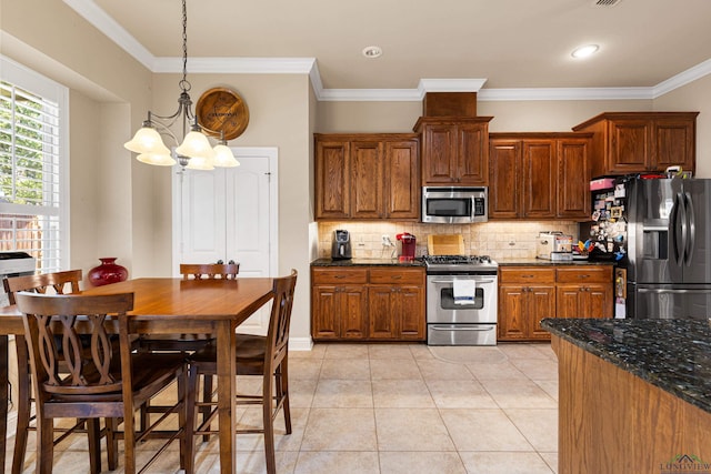 kitchen featuring dark stone counters, an inviting chandelier, hanging light fixtures, light tile patterned floors, and appliances with stainless steel finishes