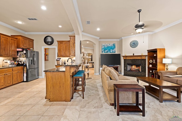 kitchen featuring ceiling fan, decorative backsplash, ornamental molding, a kitchen bar, and kitchen peninsula