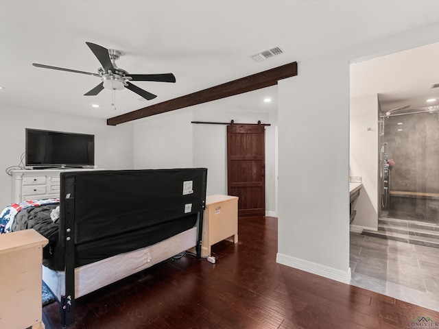 bedroom featuring dark hardwood / wood-style flooring, a barn door, ceiling fan, and connected bathroom