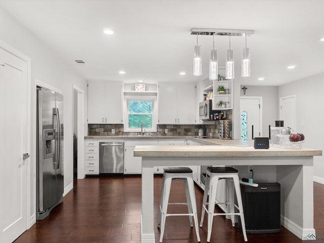 kitchen with tasteful backsplash, a breakfast bar, stainless steel appliances, pendant lighting, and white cabinets