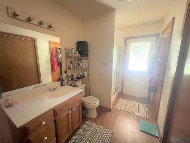 bathroom with walk in shower, vanity, a textured ceiling, wood-type flooring, and toilet