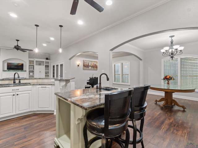 kitchen featuring sink, an island with sink, white cabinets, and stone countertops