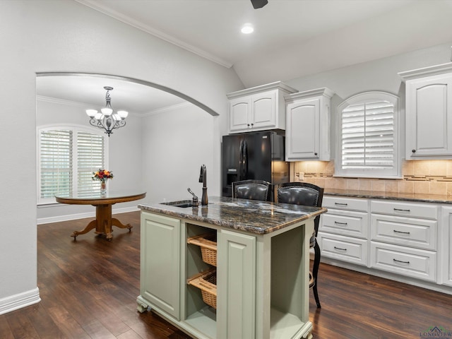 kitchen with a kitchen island with sink, white cabinets, dark stone counters, and black refrigerator with ice dispenser