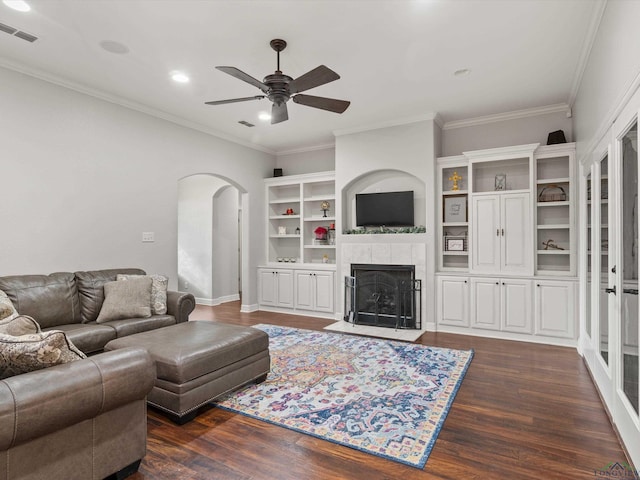 living room with a tiled fireplace, crown molding, dark hardwood / wood-style floors, and ceiling fan