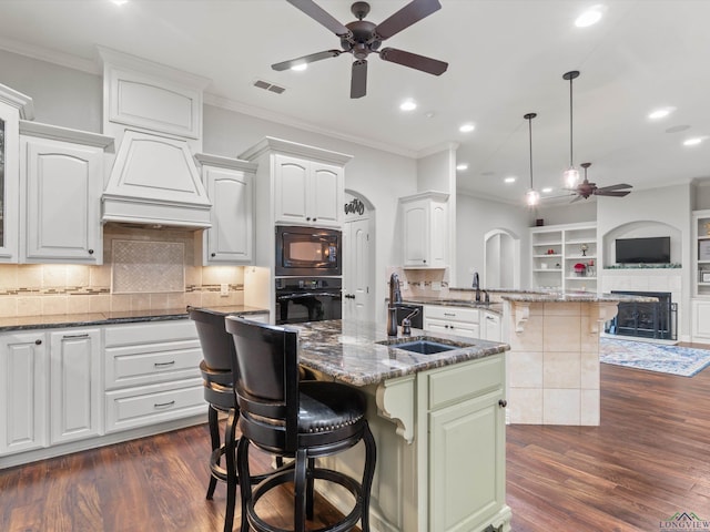 kitchen featuring a breakfast bar area, black appliances, a center island, and white cabinets