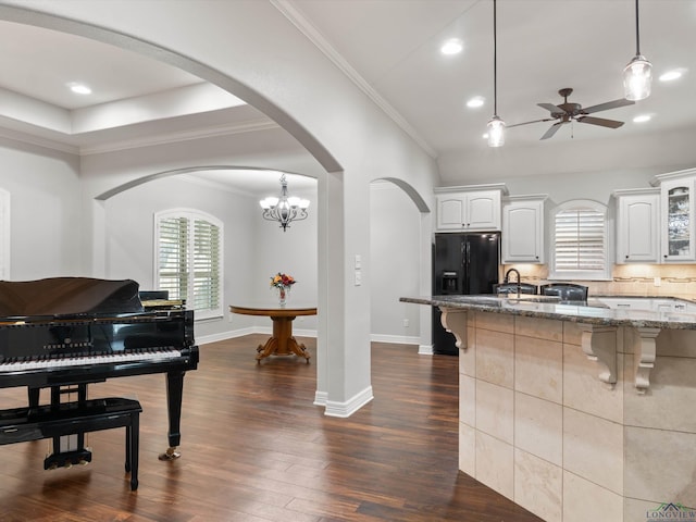 kitchen featuring decorative light fixtures, a breakfast bar, white cabinets, and dark stone counters