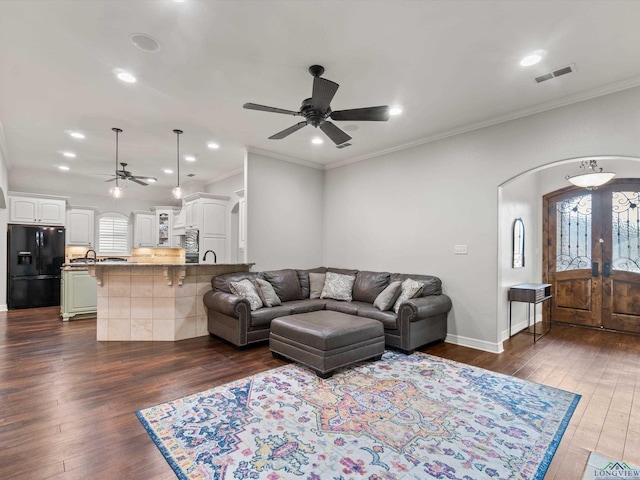 living room with crown molding, plenty of natural light, dark wood-type flooring, and ceiling fan