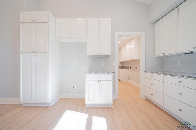 kitchen with light stone countertops, white cabinetry, and light hardwood / wood-style flooring