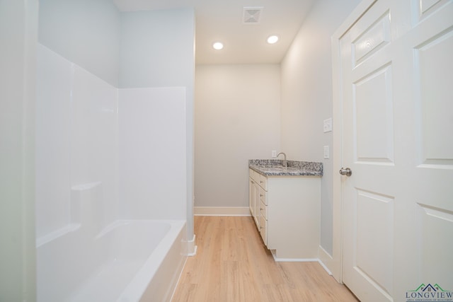 bathroom featuring a washtub, vanity, and wood-type flooring