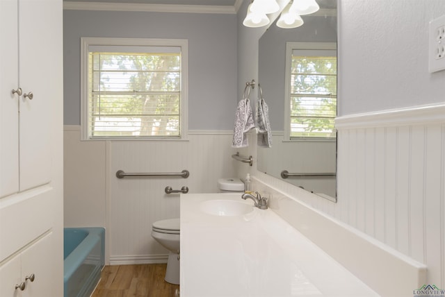 bathroom with a bathing tub, a healthy amount of sunlight, toilet, and wood-type flooring