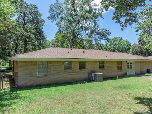 rear view of house with a yard and cooling unit