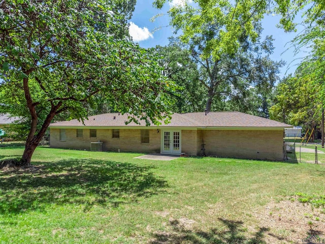 rear view of house featuring a yard, central AC, and french doors