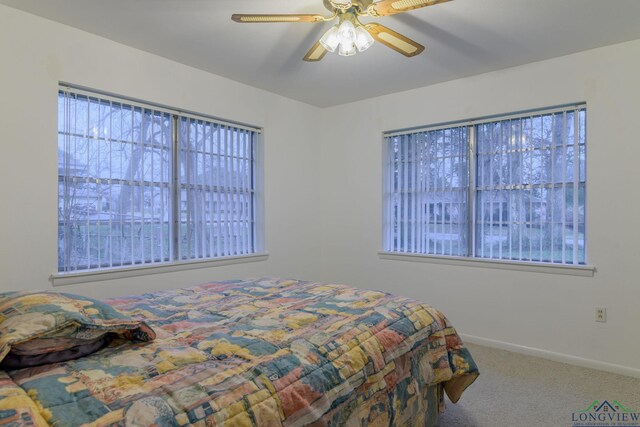 carpeted bedroom featuring multiple windows and ceiling fan