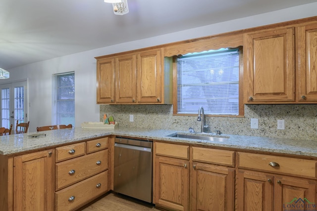 kitchen featuring sink, kitchen peninsula, light stone countertops, and dishwasher