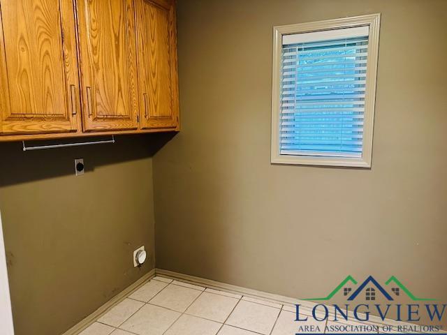 laundry room featuring cabinets, plenty of natural light, electric dryer hookup, and light tile patterned flooring