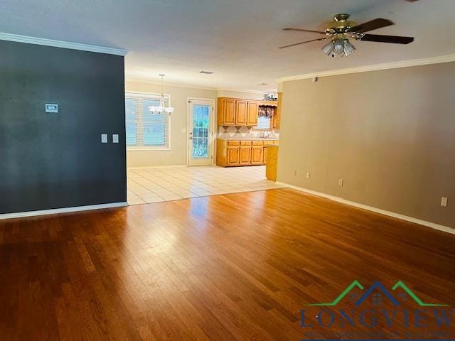 unfurnished living room featuring crown molding, light hardwood / wood-style flooring, and ceiling fan with notable chandelier