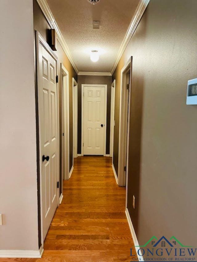 corridor featuring hardwood / wood-style flooring, crown molding, and a textured ceiling