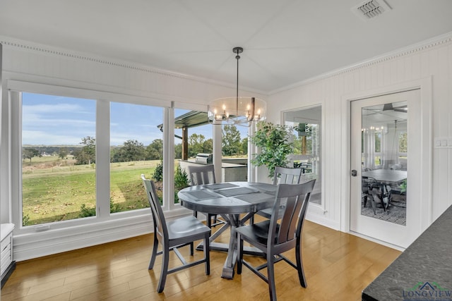 dining room featuring visible vents, light wood-style flooring, an inviting chandelier, ornamental molding, and a healthy amount of sunlight