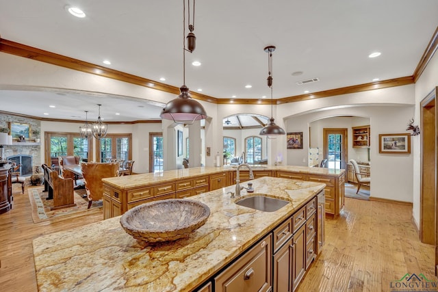 kitchen with light wood-type flooring, visible vents, a sink, and a large island