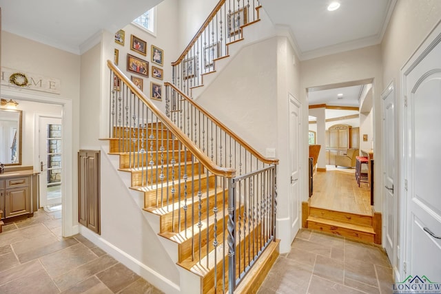 staircase featuring stone tile floors, baseboards, a high ceiling, crown molding, and recessed lighting